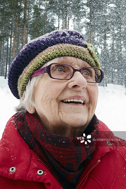 面带微笑的年长女人看雪花飘落图片素材