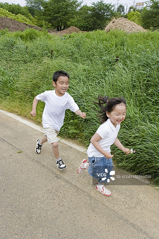 在日本东京都町田市玩标签游戏的小男孩和女孩图片素材