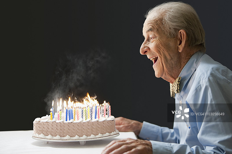 年长的西班牙裔男人吹灭生日蜡烛图片素材