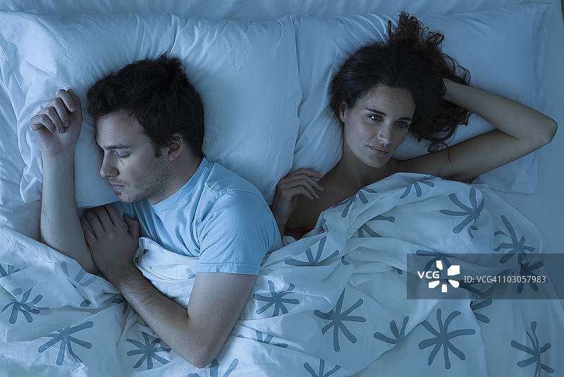 情侣一起躺在床上，女人不安地醒着图片素材