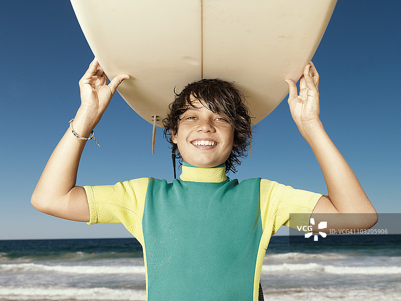 在海滩上拿着冲浪板的男孩图片素材