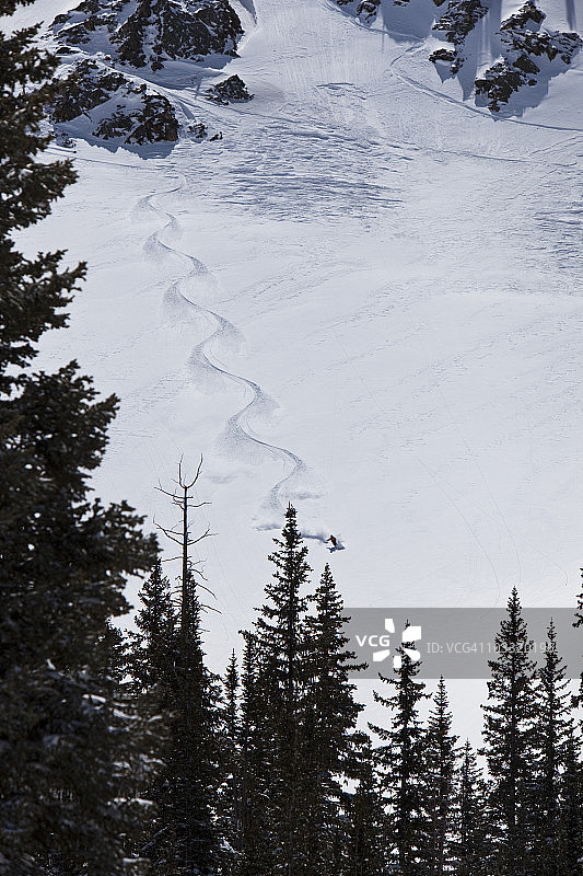 在犹他州阳光明媚的日子里，滑雪男子在未被扰动的粉雪上滑行图片素材