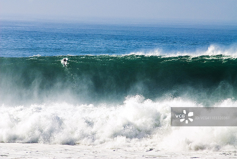 冲浪者在加利福尼亚州圣地亚哥黑人海滩划过巨浪图片素材