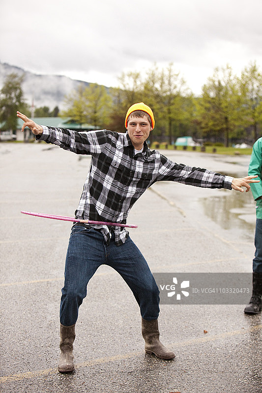 雨后停车场，年轻男人笑着玩呼啦圈图片素材
