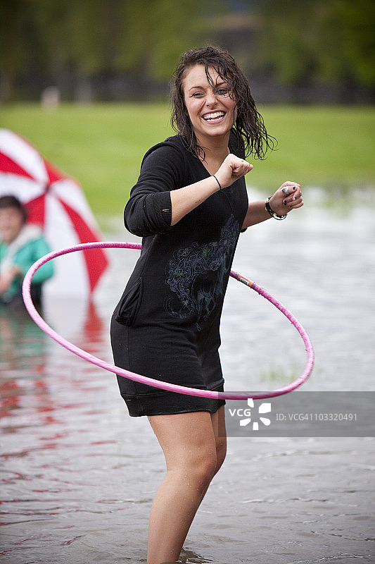 年轻女子在雨后的大水坑里玩呼啦圈图片素材