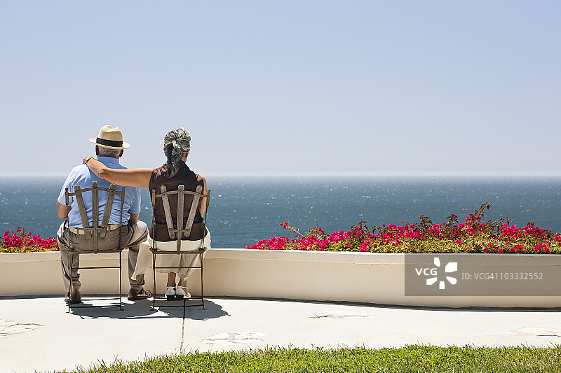 老年夫妇坐在可以俯瞰海洋的露台上图片素材