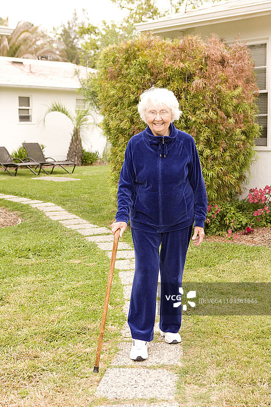 面带微笑的老奶奶拄着拐杖行走图片素材