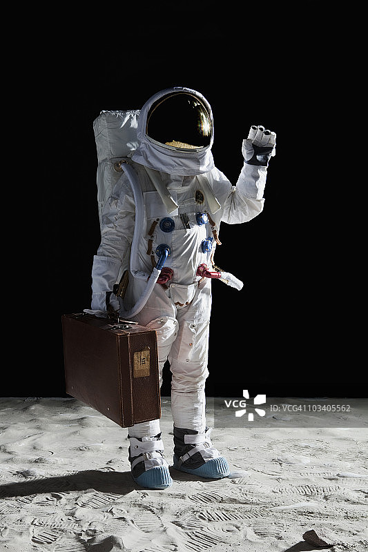 在月球上手提箱并挥手的宇航员图片素材