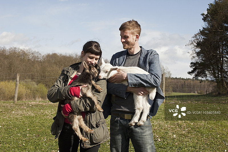 一对夫妇抱着小山羊图片素材