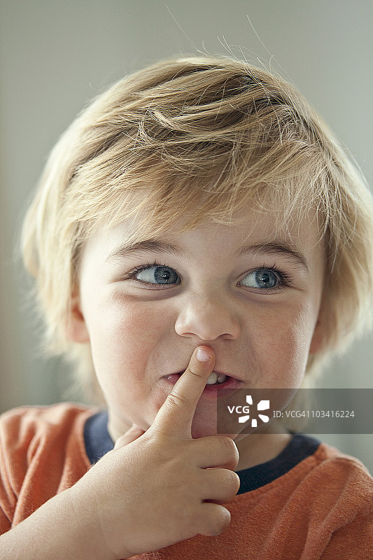 2岁的年轻男孩用手指着嘴巴图片素材