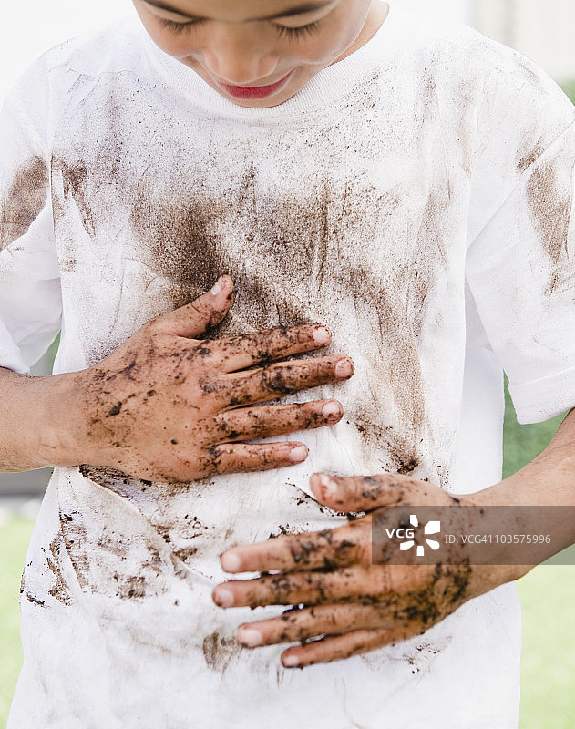 混血男孩在衬衫上擦拭脏手图片素材