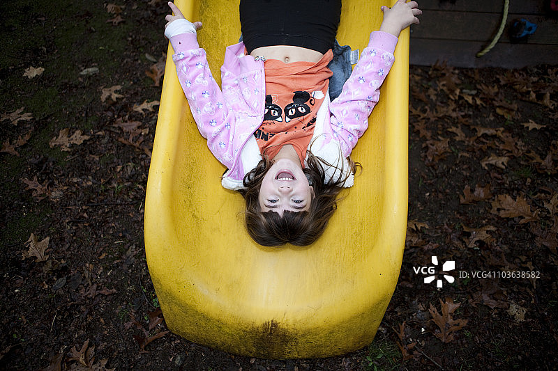 在黄色滑梯上倒立的小女孩图片素材