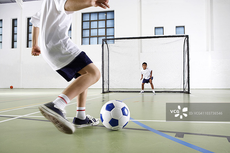 男孩在体育馆里踢球图片素材