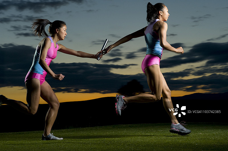 接力赛跑者在比赛中传递接力棒图片素材