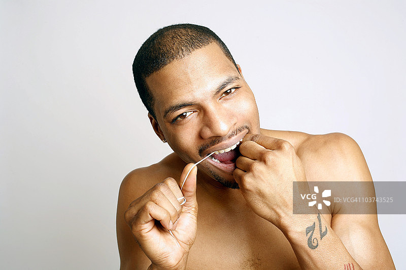 年轻的非洲裔美国男子用牙线清洁牙齿图片素材