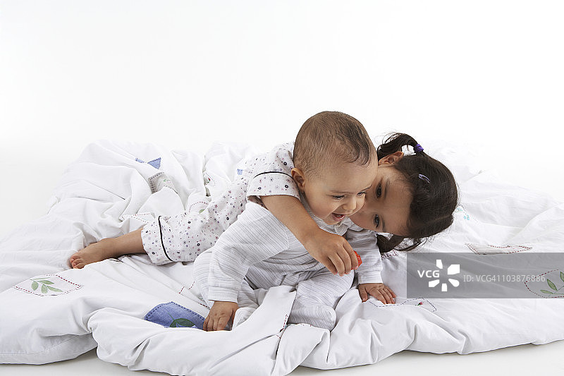 幼儿在床上拥抱她的弟弟图片素材