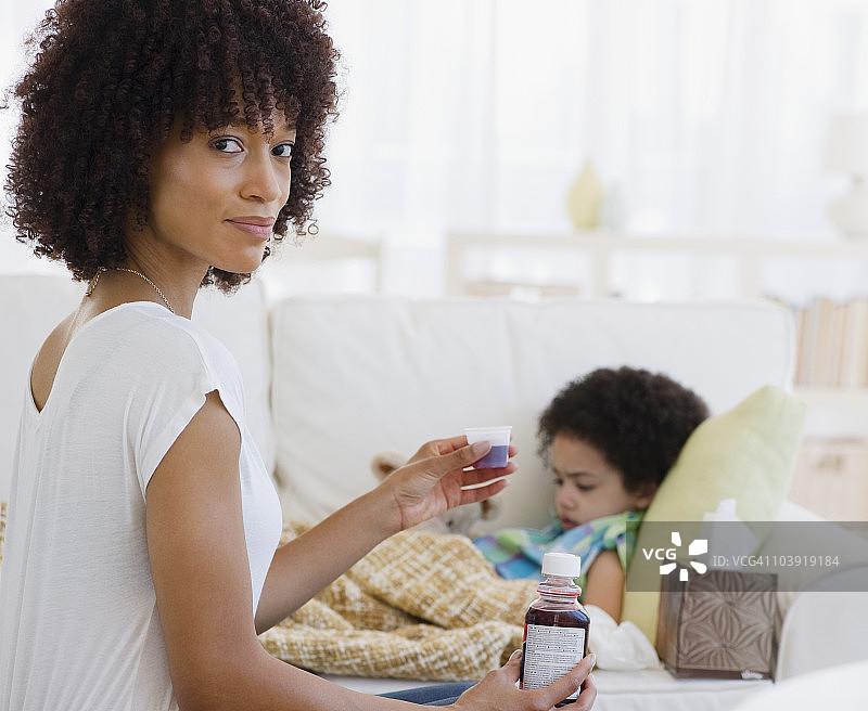 母亲给生病的女儿喂止咳糖浆图片素材