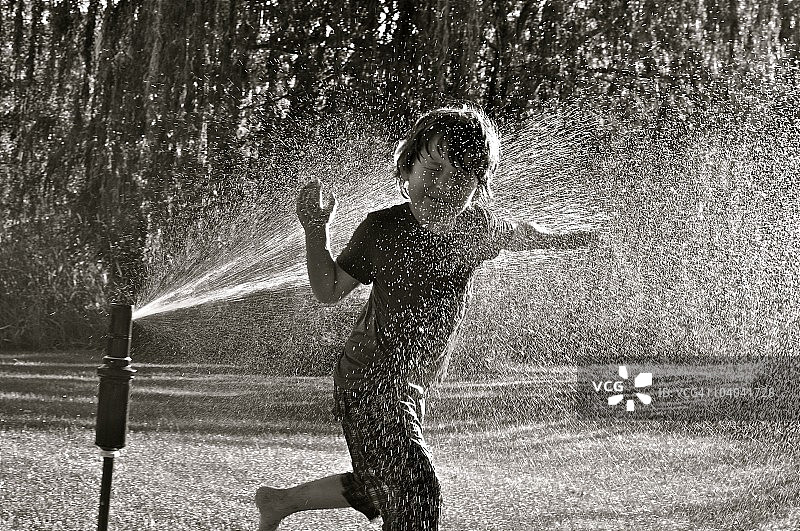 在洒水器中的男孩图片素材