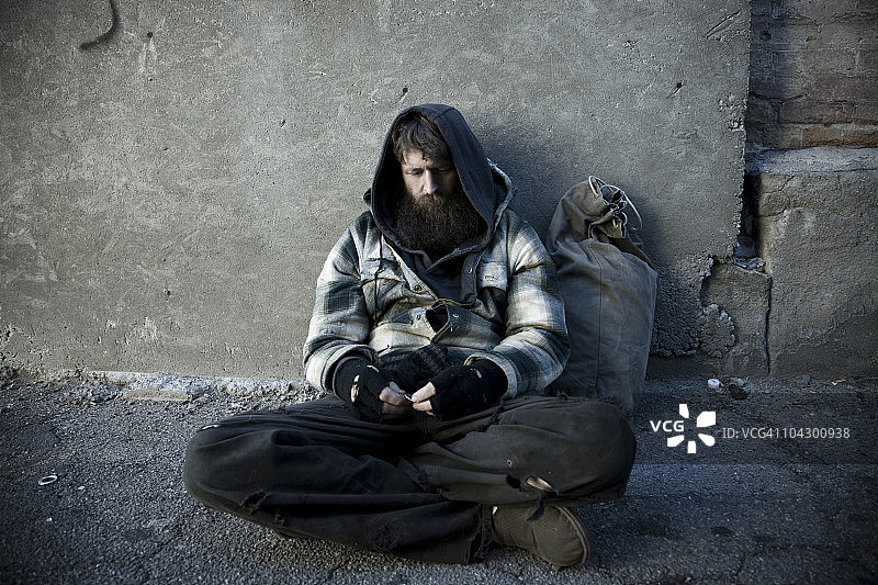 美国犹他州盐湖城：无家可归的男人带着麻袋坐在人行道上图片素材