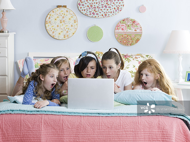 五个女孩在床上使用笔记本电脑图片素材
