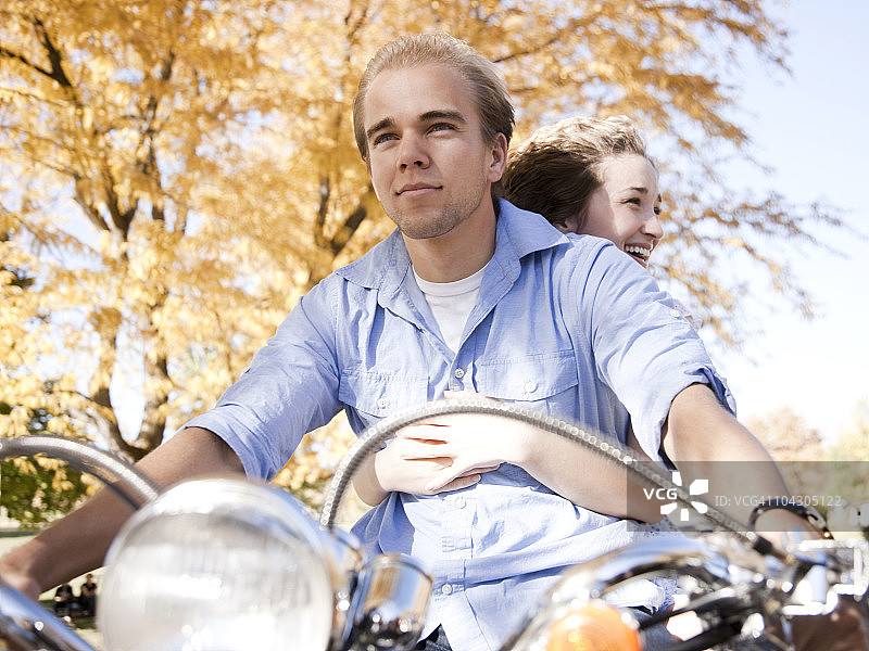 年轻夫妇在秋季森林中骑摩托车图片素材