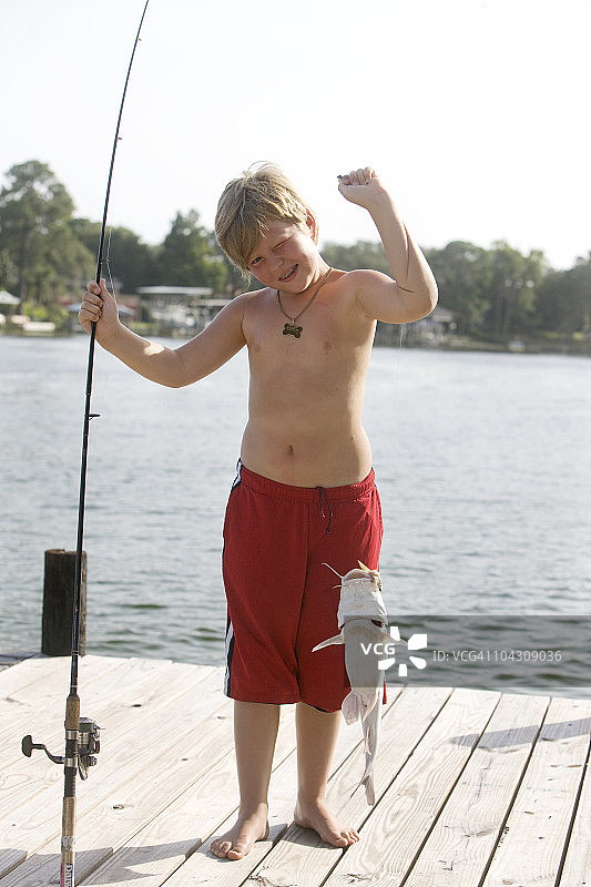 男孩在码头上举着鱼图片素材