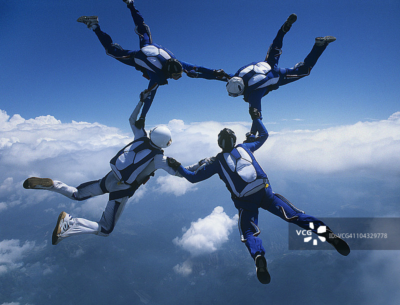 四名跳伞员手拉手，云层背景图片素材