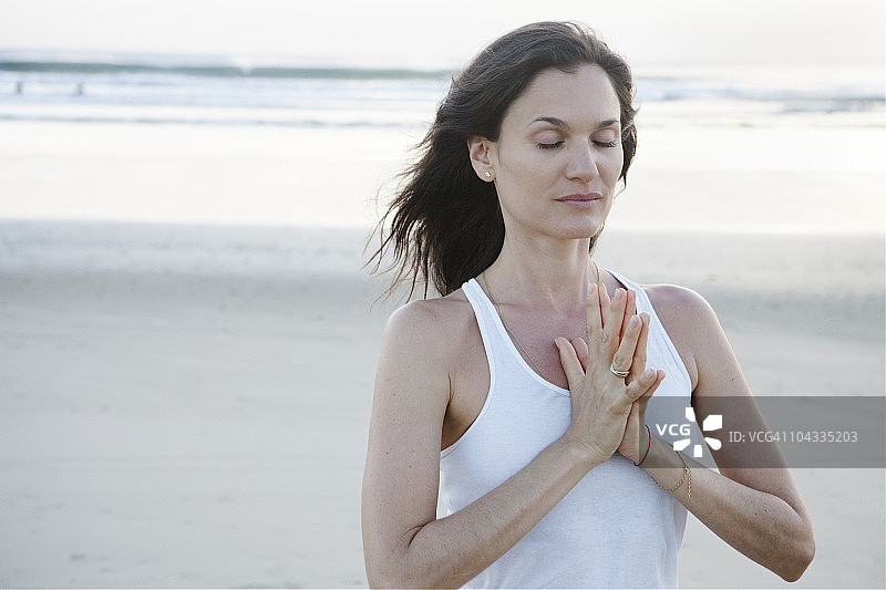 在海滩做瑜伽的年轻女人图片素材
