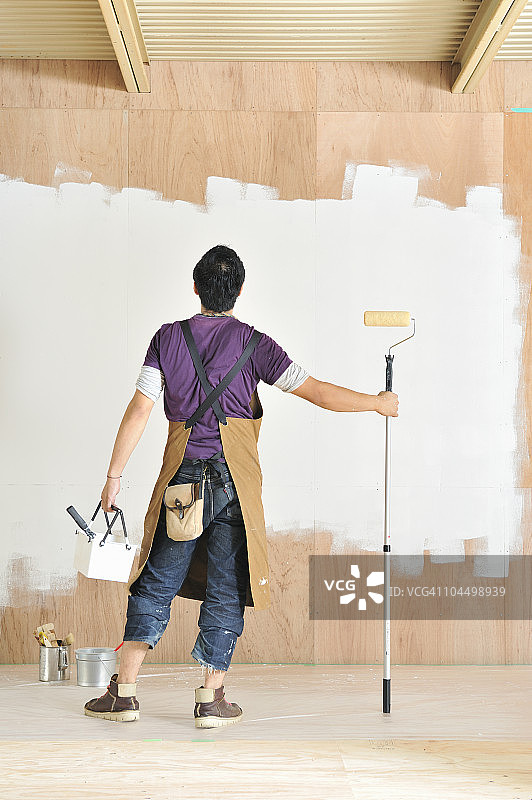 男人粉刷墙壁，后视图图片素材