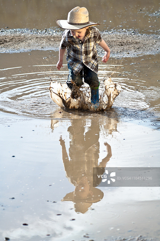 跳过泥水坑的小男孩图片素材