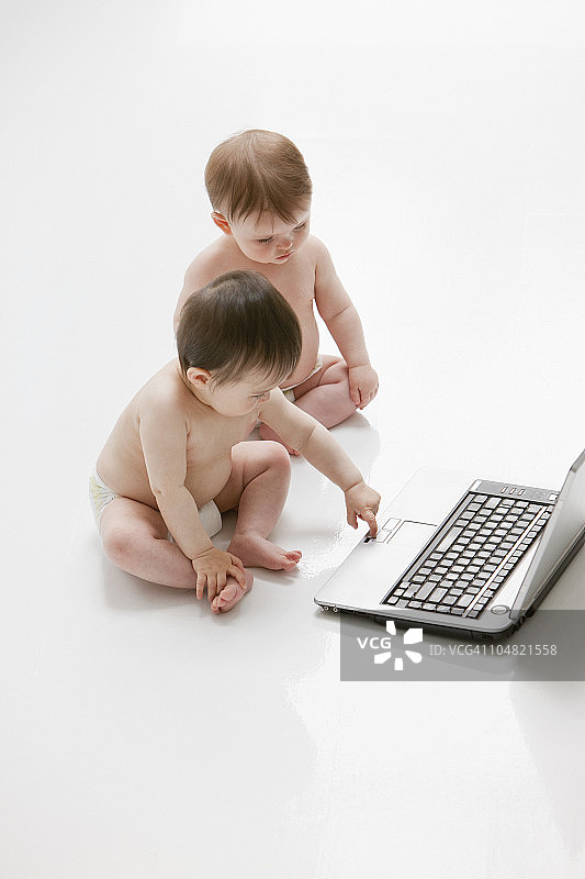 在地板上使用笔记本电脑的婴儿图片素材
