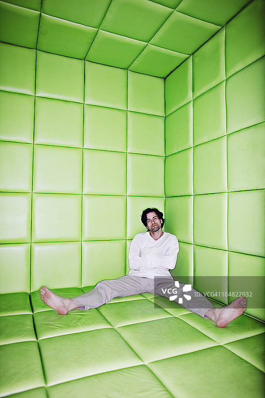 男子坐在软垫房间里，双腿分开图片素材