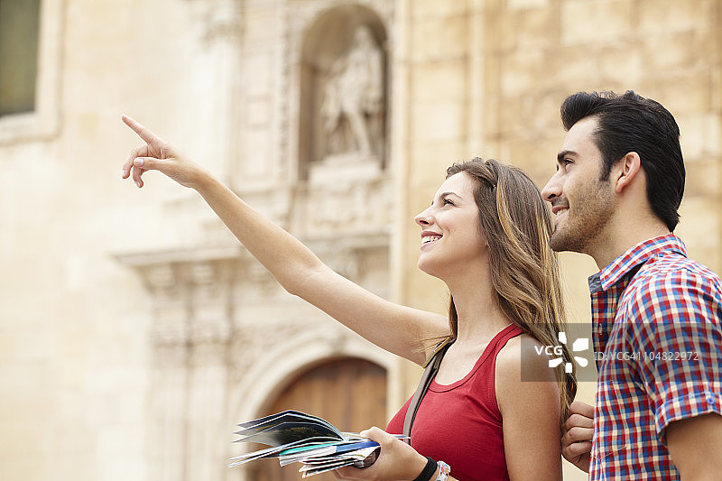 微笑的年轻女人指着景点图片素材