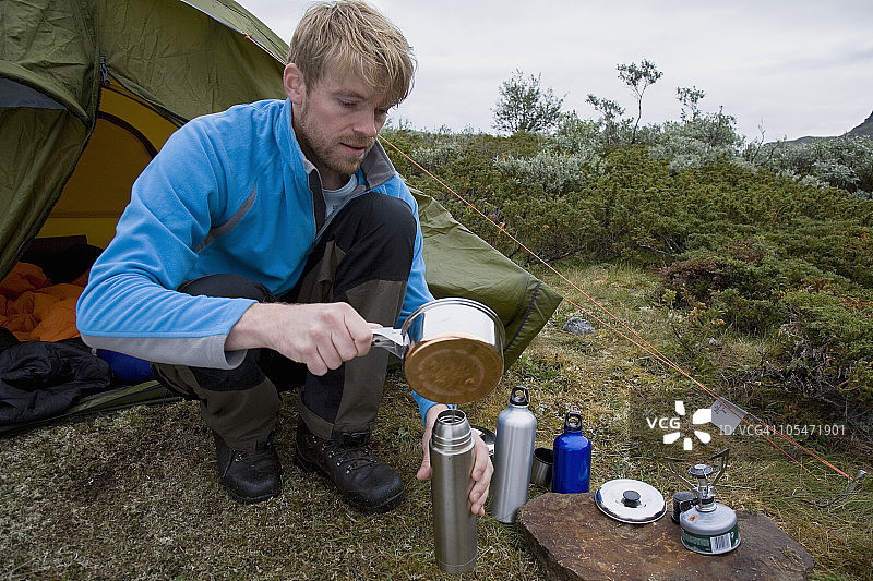 在帐篷外向烧瓶中倒入热水图片素材