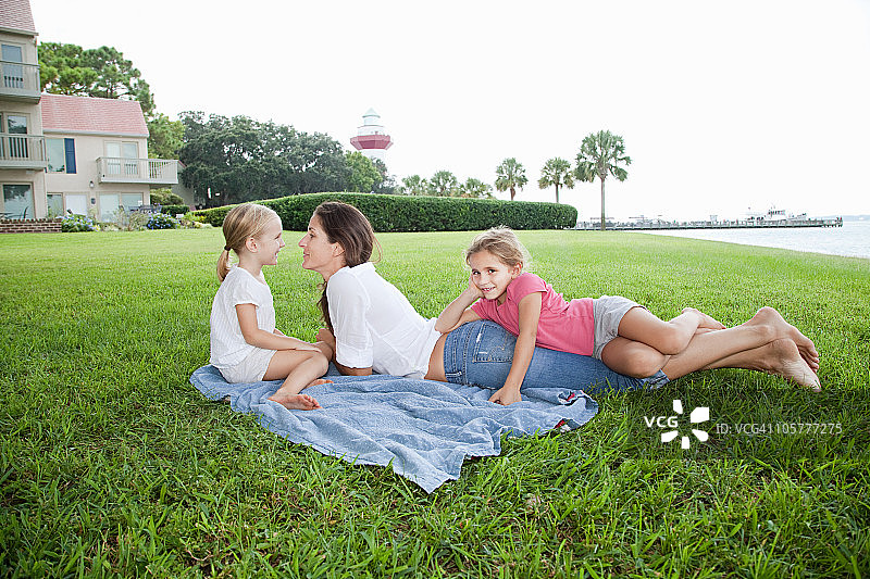 快乐的母亲和女儿们躺在草地上图片素材