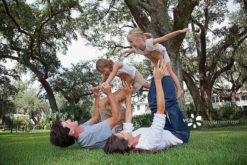 女孩站在父母的脚上保持平衡图片素材