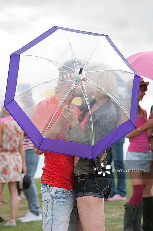 年轻夫妇在节日期间于雨伞后亲吻图片素材