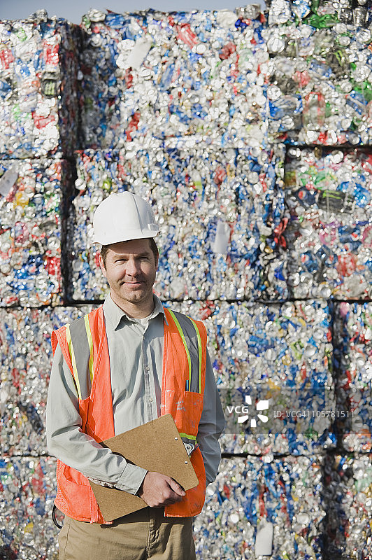 工人站在压碎的铝罐前图片素材
