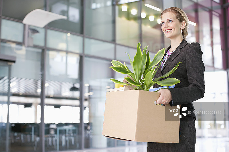 carrying a cardboard box with a potted plant图片素材