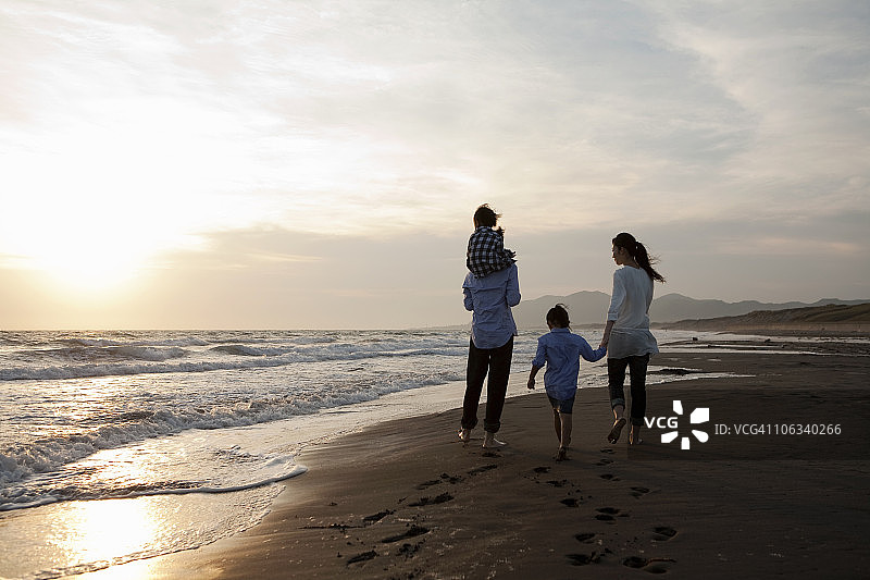一家人在傍晚的海滩上散步图片素材