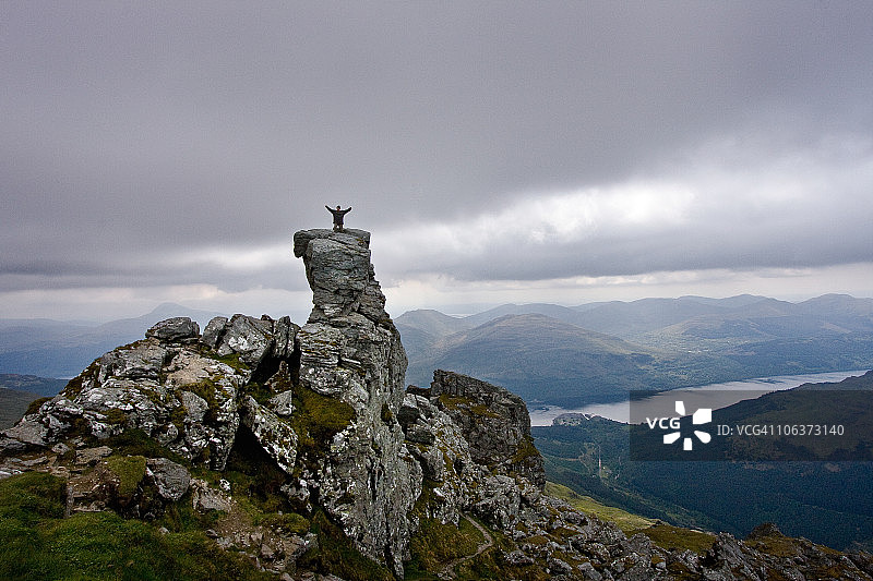 站在岩石尖顶上观察风景的人图片素材