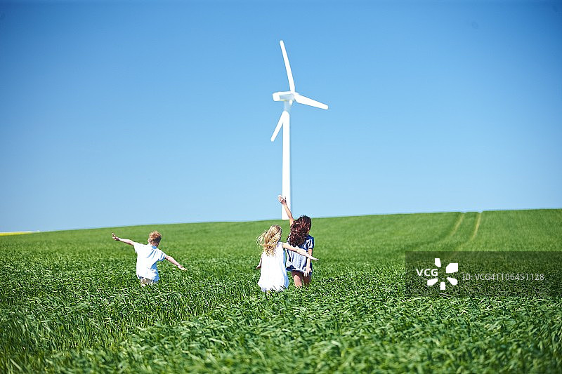 风力涡轮机与田野中的儿童嬉戏图片素材