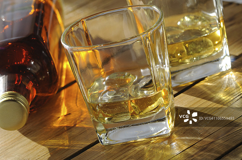 阳光下的两杯冰镇威士忌和酒瓶图片素材