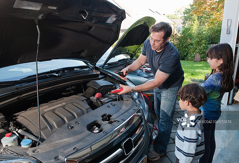 父亲将跨接电缆连接到汽车上图片素材