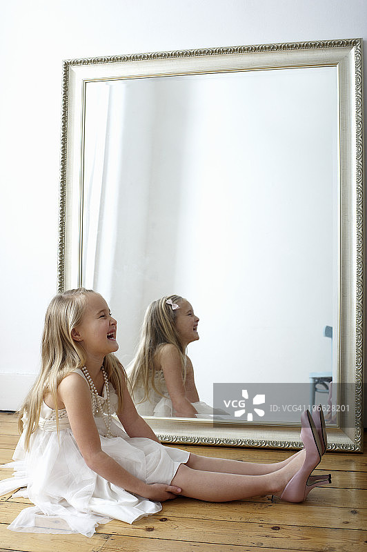 笑着穿妈妈鞋子的女孩肖像图片素材