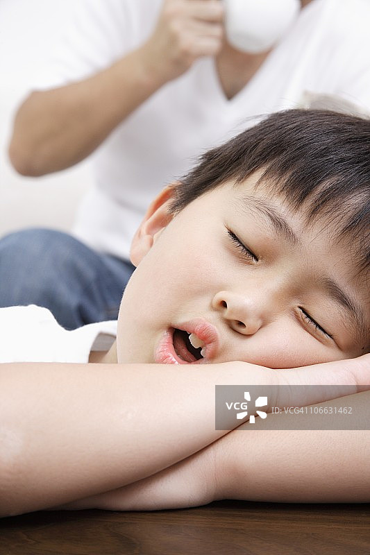 和拿着杯子的父亲一起睡觉的男孩图片素材