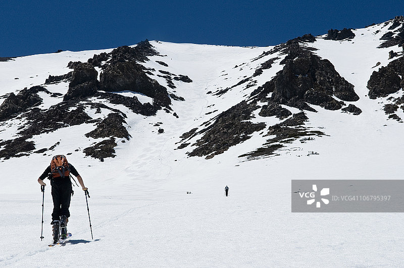 在他本季的最后一次滑雪之旅中，一位年轻人在加利福尼亚州六月湖攀登顶峰图片素材