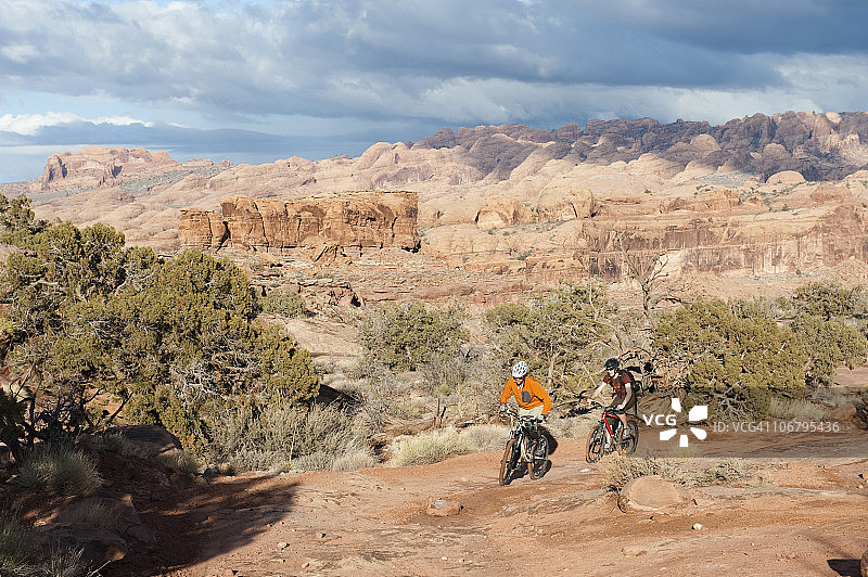 在犹他州摩押的阿马萨小道上骑自行车的两位年轻人图片素材