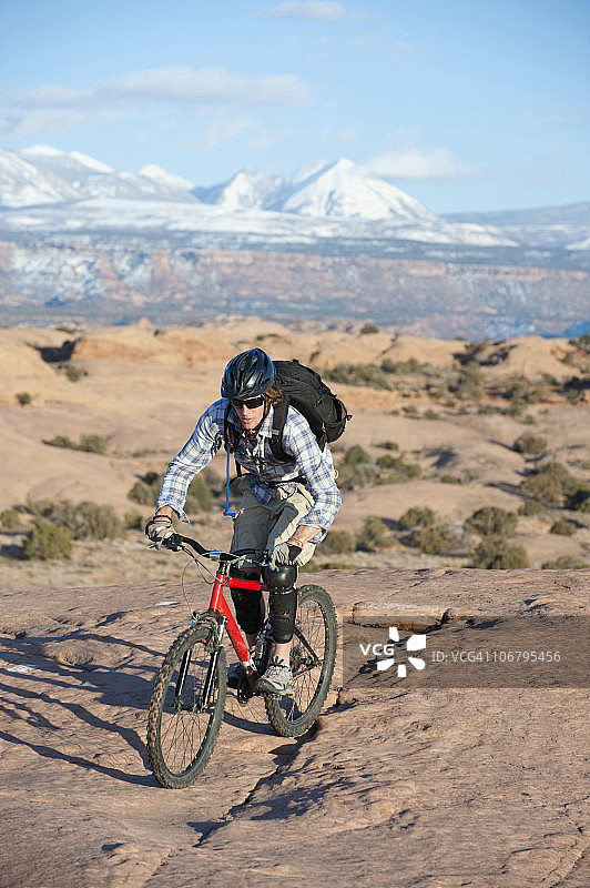 年轻人在犹他州莫阿布的斯利克罗克小径上骑山地自行车图片素材