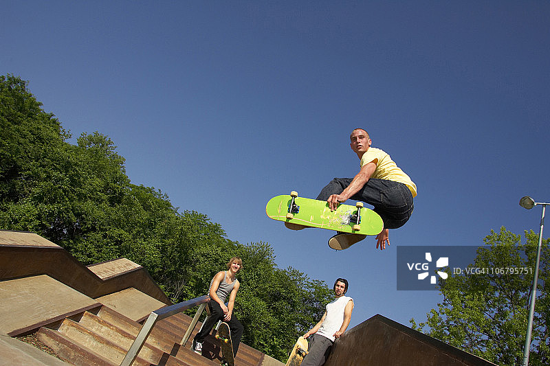 三位滑板运动员在滑板公园表演技巧图片素材